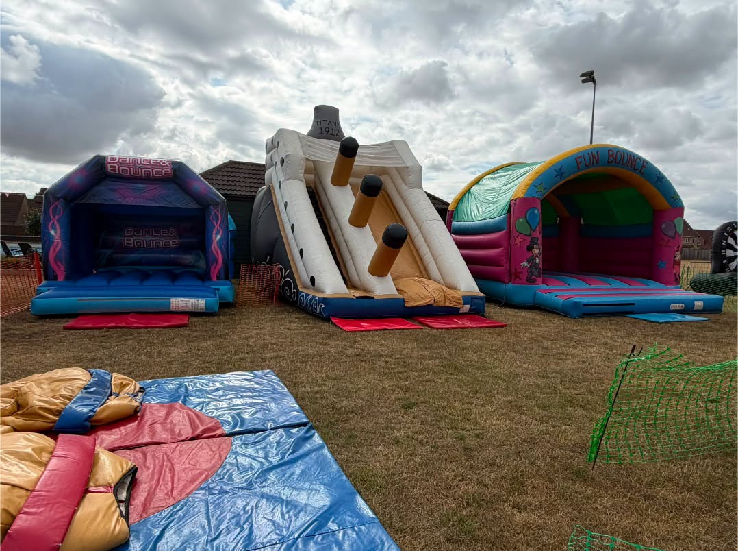 Inflatable bouncy castles and a slide set up on the club field for a summer fun day